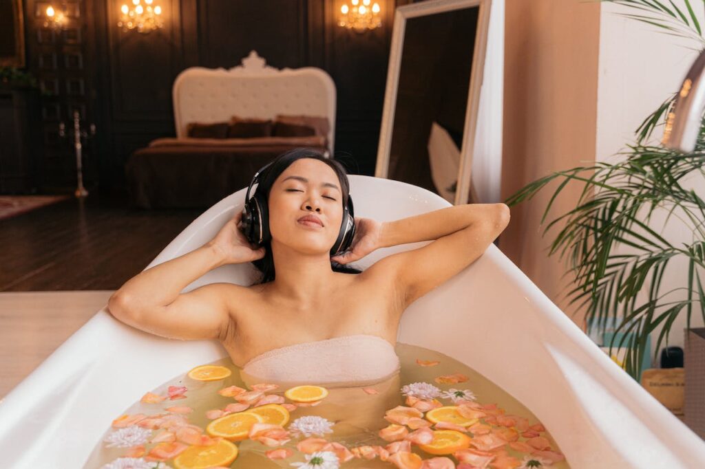 A woman relaxing in a bathtub with headphones on, listening to ASMR and understanding ASMR and it's impact on mental health.